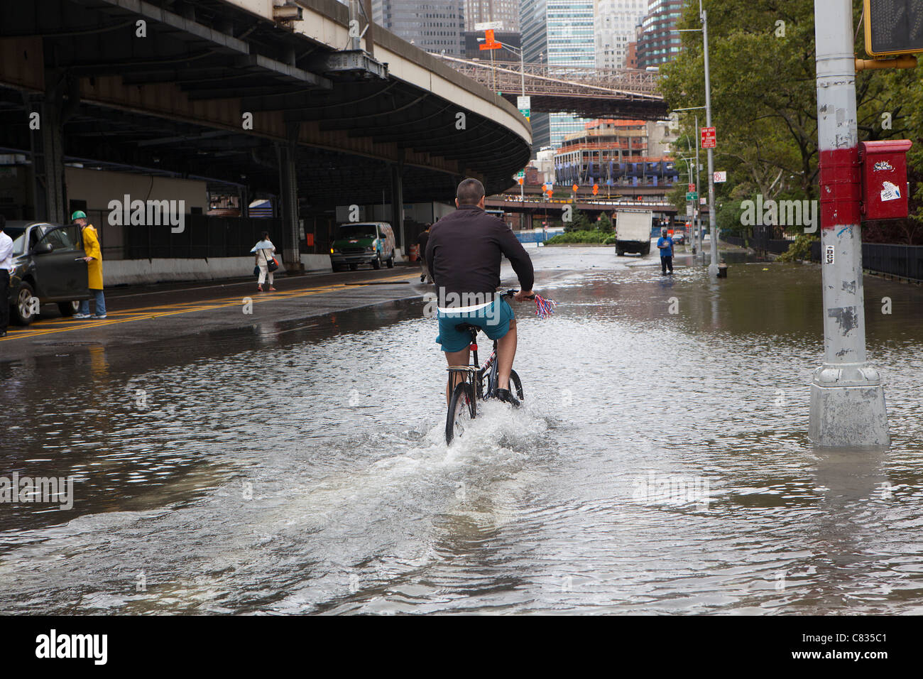 Biker en calle inundada bajo el puente de Manhattan, Nueva York, durante el huracán Irene. La Ciudad de Nueva York, EE.UU. Foto de stock