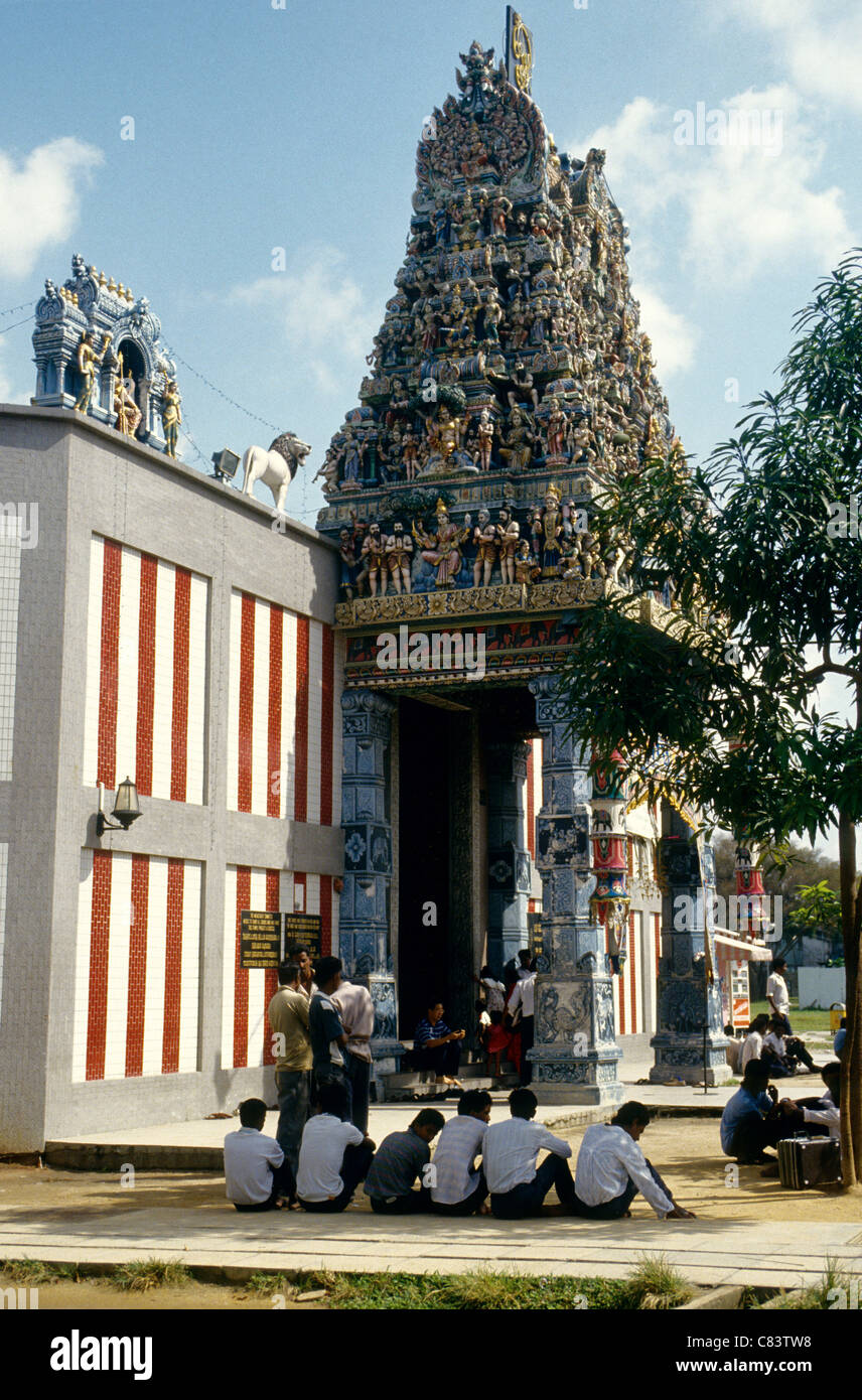 Los hombres jóvenes sentados a la sombra de un templo hindú en Singapur. Foto de stock