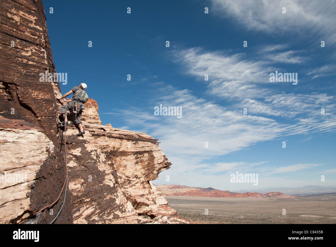 Un escalador es ascendente algunos grandes rocas areniscas de color rojo, cerca de las vegas, en Nevada. Foto de stock