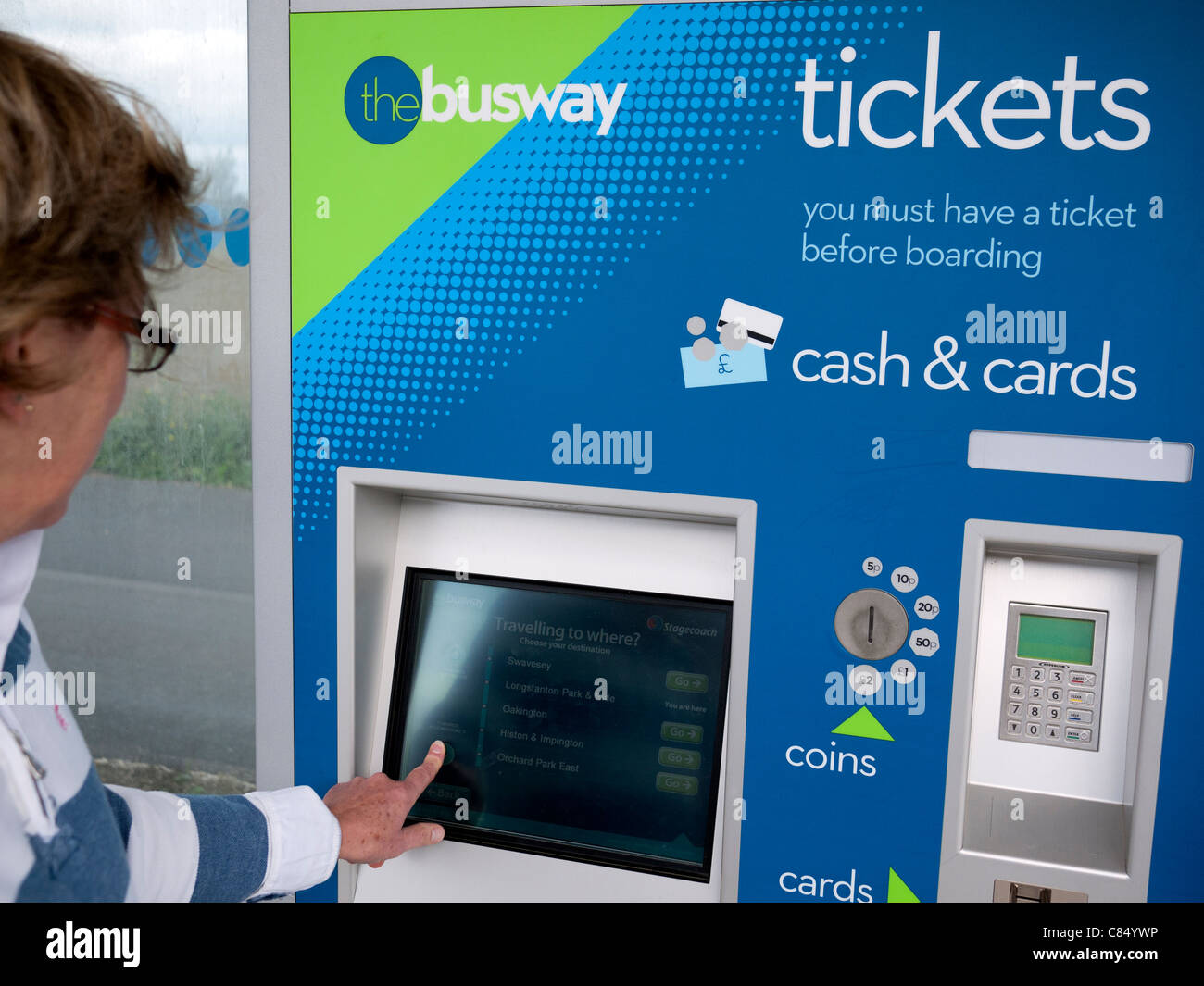 Una mujer compra un ticket de la máquina automática del billete en la guiada Cambridgeshire Busway cerca de Cambridge, Reino Unido Foto de stock