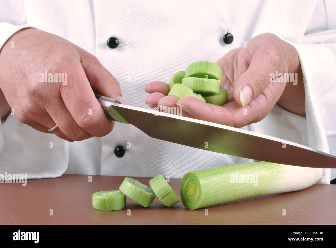 Chef femenina Corta el puerro con un gran cuchillo de cocina Foto de stock
