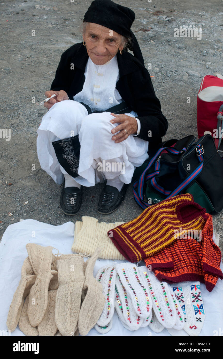 Milot village mercado dominical . Anciana con traje tradicional-vestido blanco y pantalones, delantal negro vendiendo calcetines tejidos a mano Foto de stock