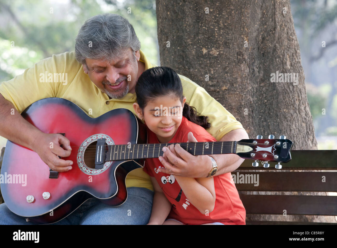 Su nieta abuelo enseñando a tocar la guitarra Foto de stock