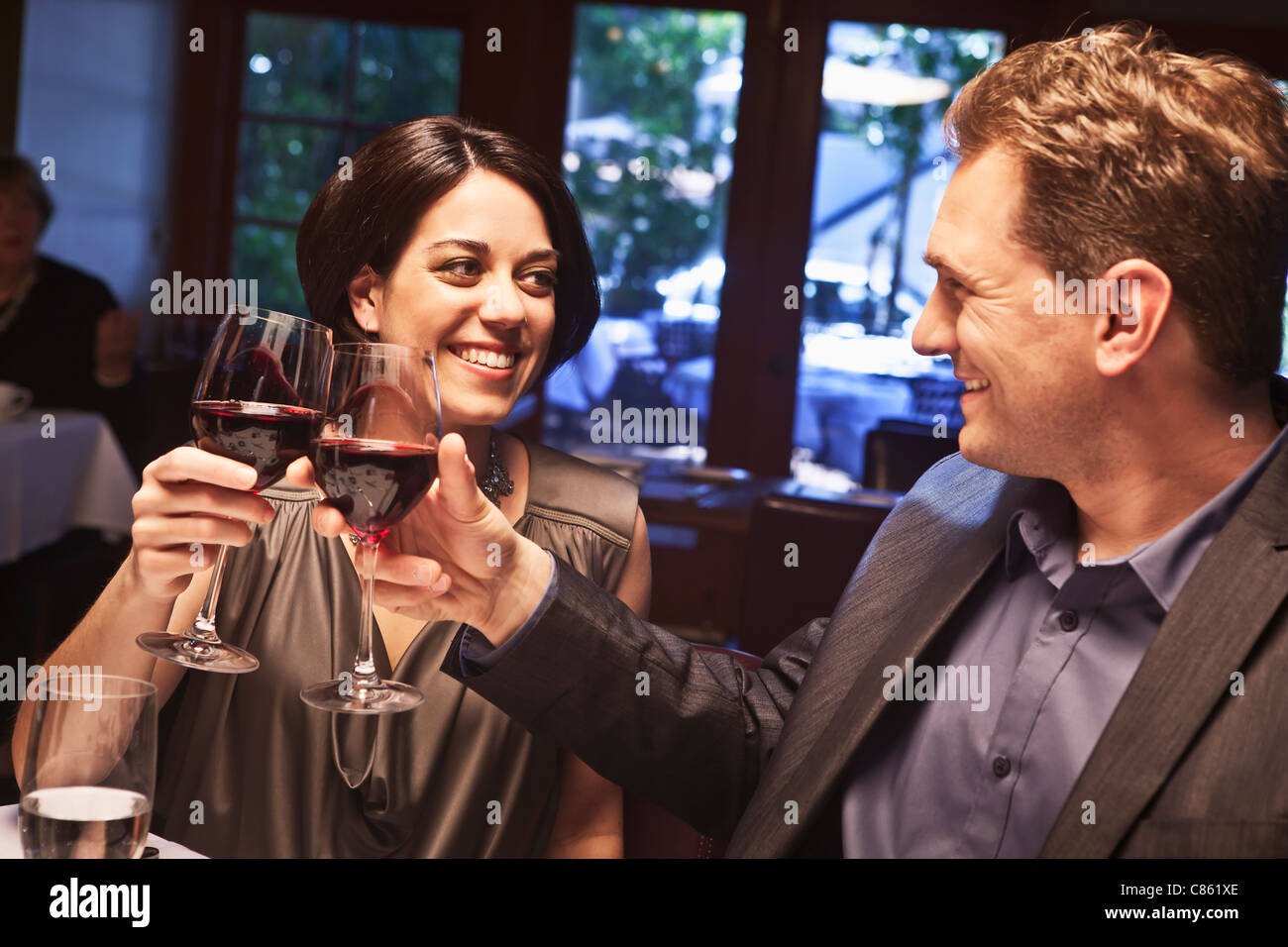 Pareja brindando con vino tinto en restaurante Foto de stock