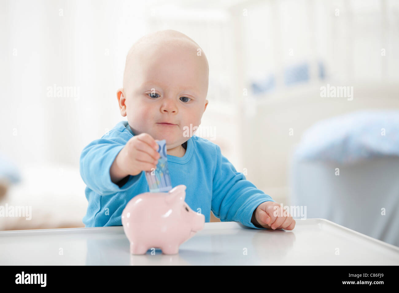 Baby Boy poner dinero en la hucha Fotografía de stock - Alamy