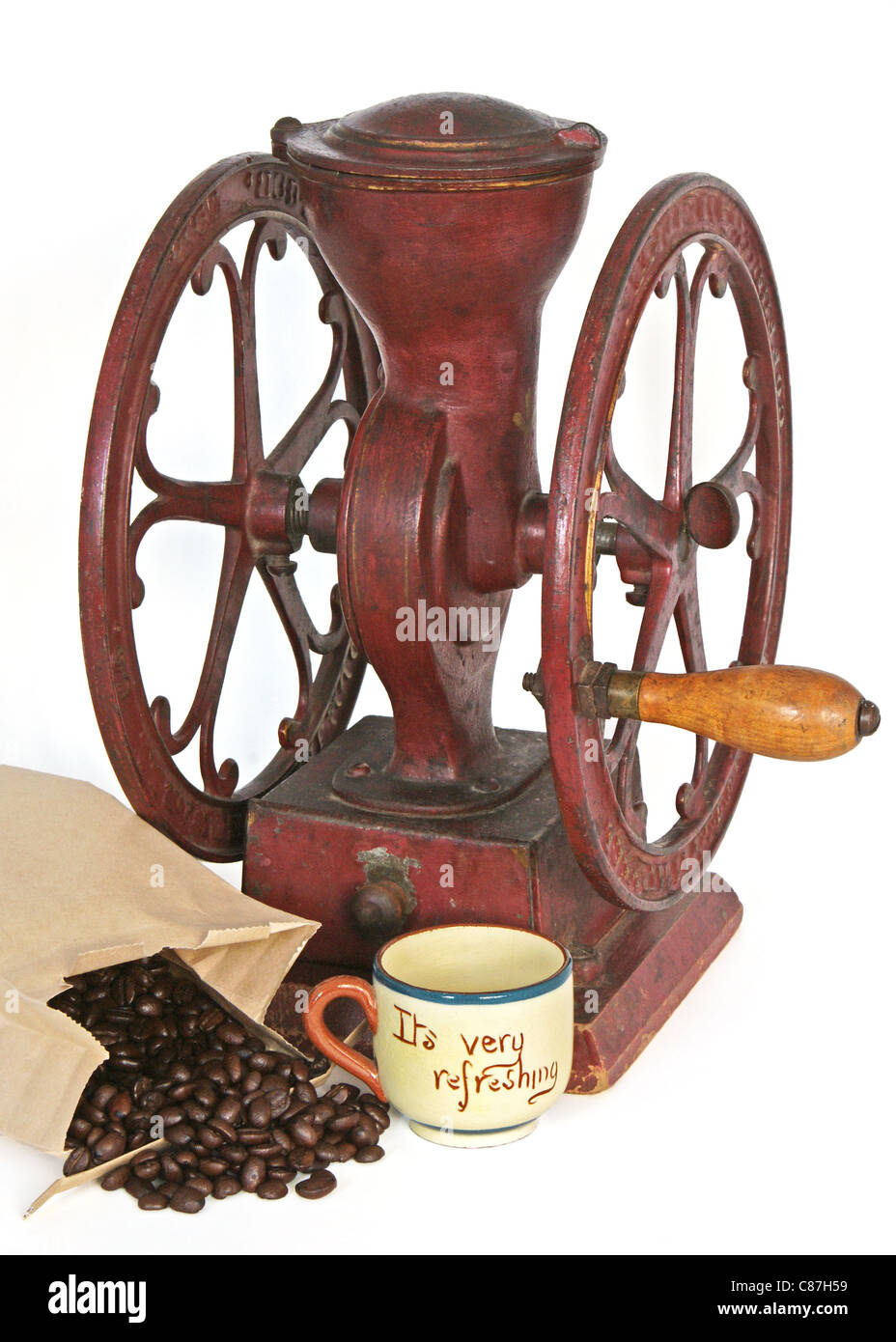 Molinillo de café antiguo de rueda roja con mango de madera cerca de  algunos granos enteros y una taza vacía Fotografía de stock - Alamy