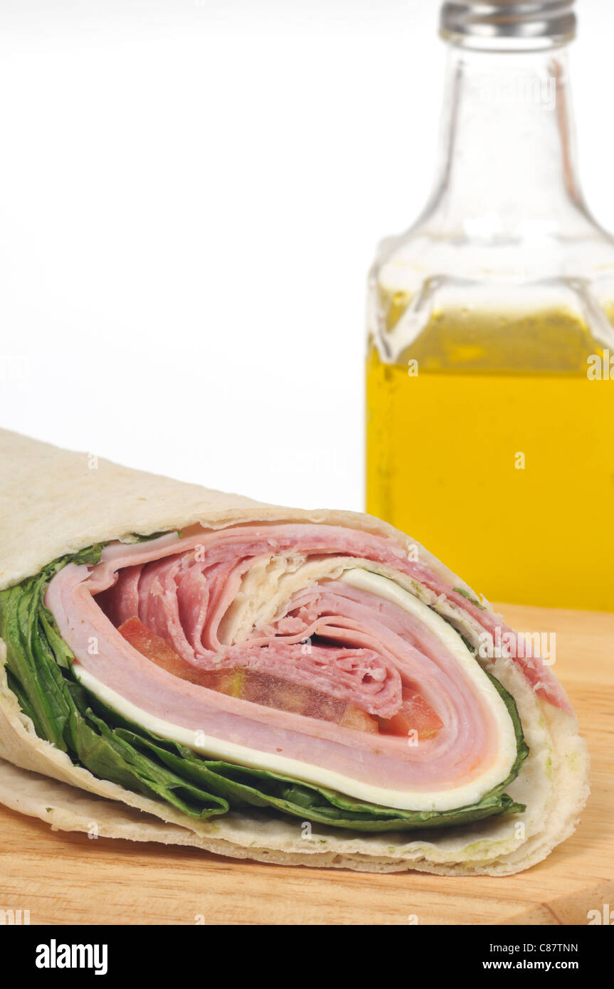 Deli italiano carne wrap sandwich con lechuga, tomate y queso y una botella de aceite de oliva sobre fondo blanco. Ee.Uu. Foto de stock