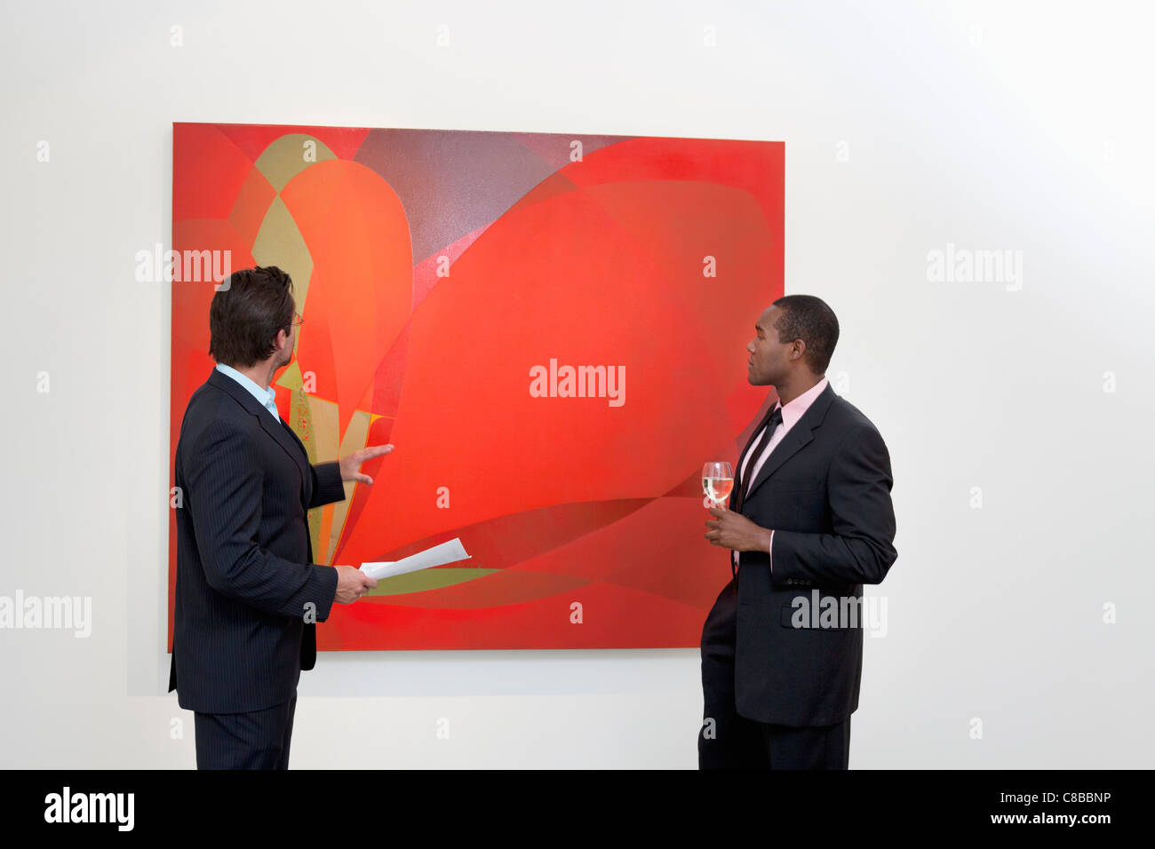 Dos hombres hablando sobre la pintura en la galería de arte Foto de stock