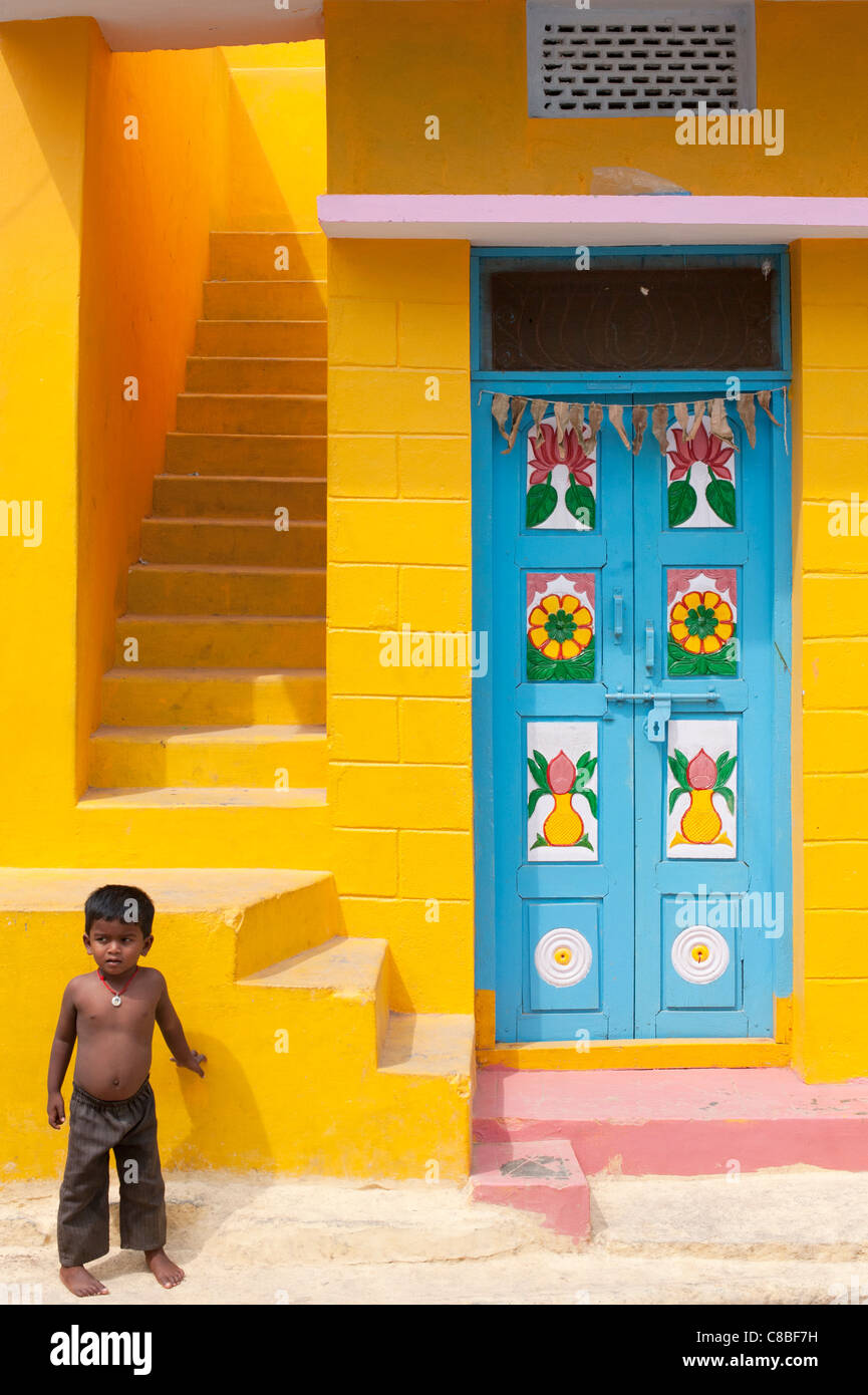 Indian bebé pie fuera un colorido Amarillo Casa de pueblo indio y la puerta azul. Andhra Pradesh. La India Foto de stock