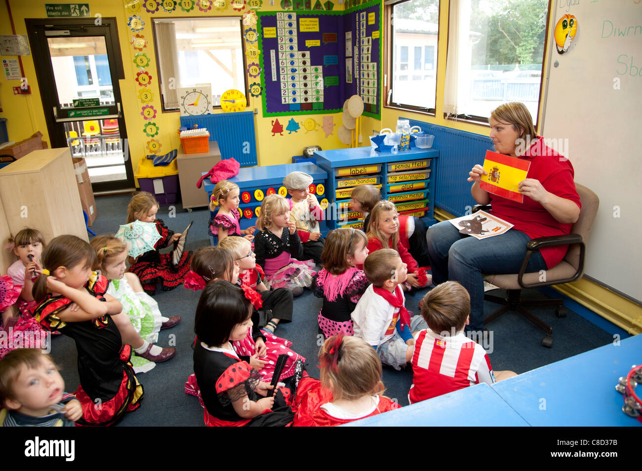 Día internacional - una maestra con los niños en la clase en una escuela primaria hablando de España, Gales, Reino Unido Foto de stock