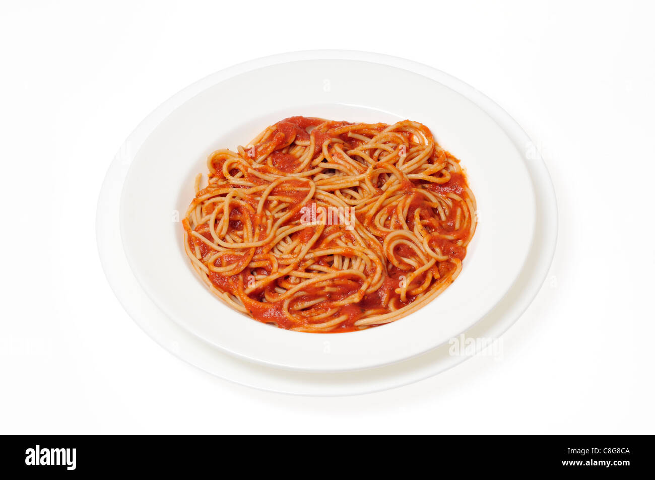 El trigo entero cocido espaguetis con salsa de tomate en el recipiente blanco sobre fondo blanco del recorte. Foto de stock