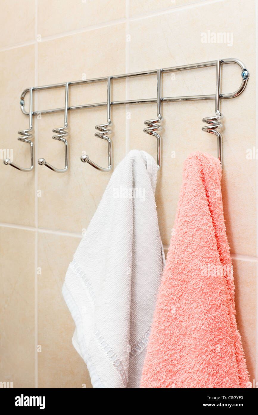 Un juego de ropa de baño que consta de una toalla y una bata está colgado  en el perchero del baño.