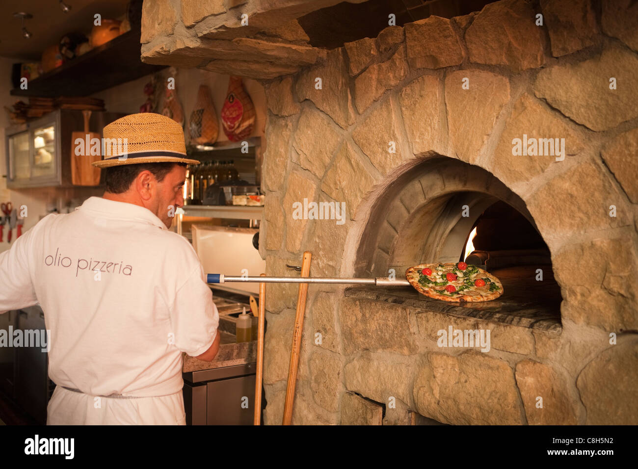 Hombre insertar paesana pizza en un horno de piedra para hornear