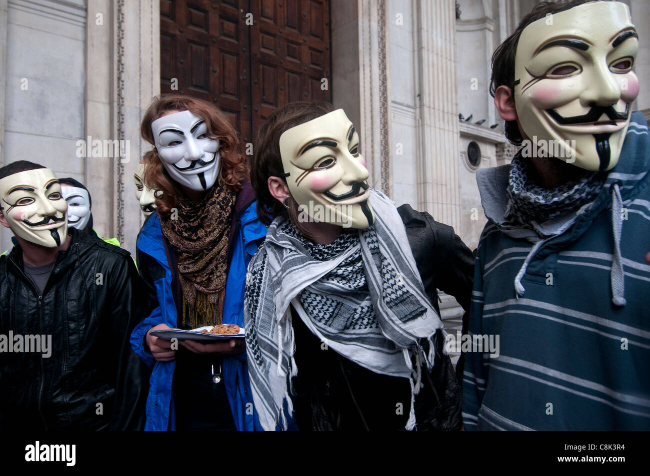 Ocupar Londres en St Paul's - Anónimo, los manifestantes portando máscaras de Guy Fawkes en frente de las puertas de la catedral cerradas Foto de stock