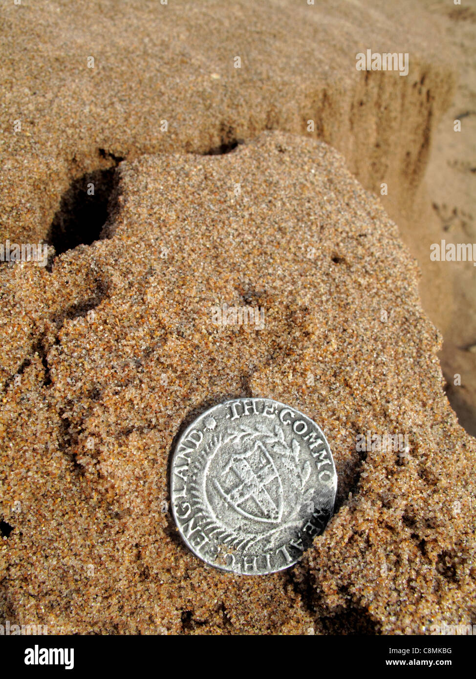 Un commonwealth chelín de plata de la época de Cromwell, descansa sobre la arena. Foto de stock