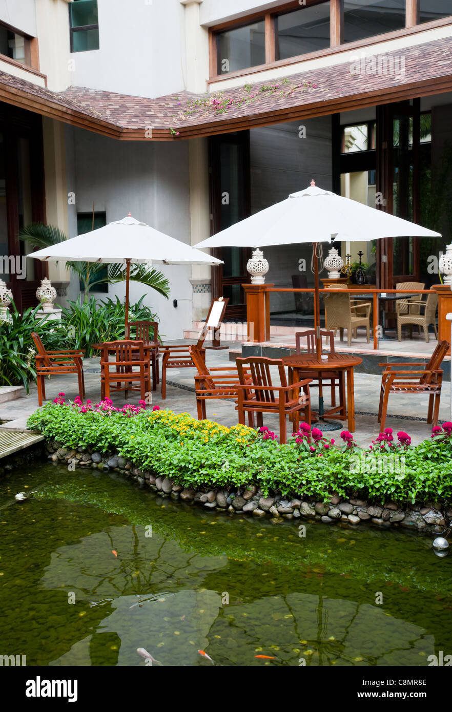 Patio jardín con sillones y sombrillas por el Waterside Foto de stock
