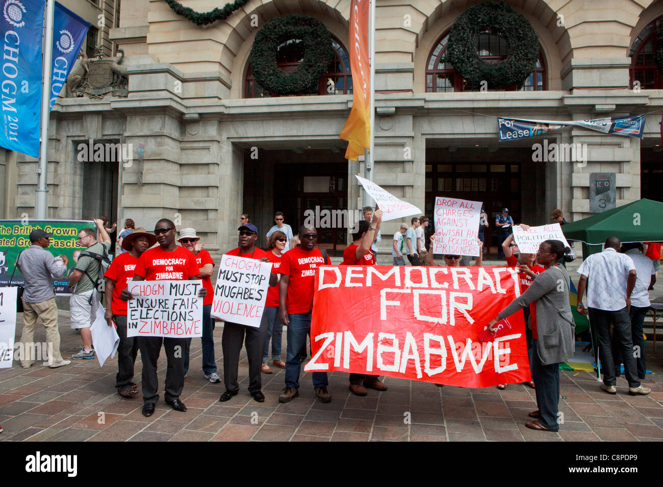Mugabe contra los manifestantes sosteniendo un 'Democracia para Zimbabwe" banner en CHOGM 2011 protestas en Perth. Foto de stock