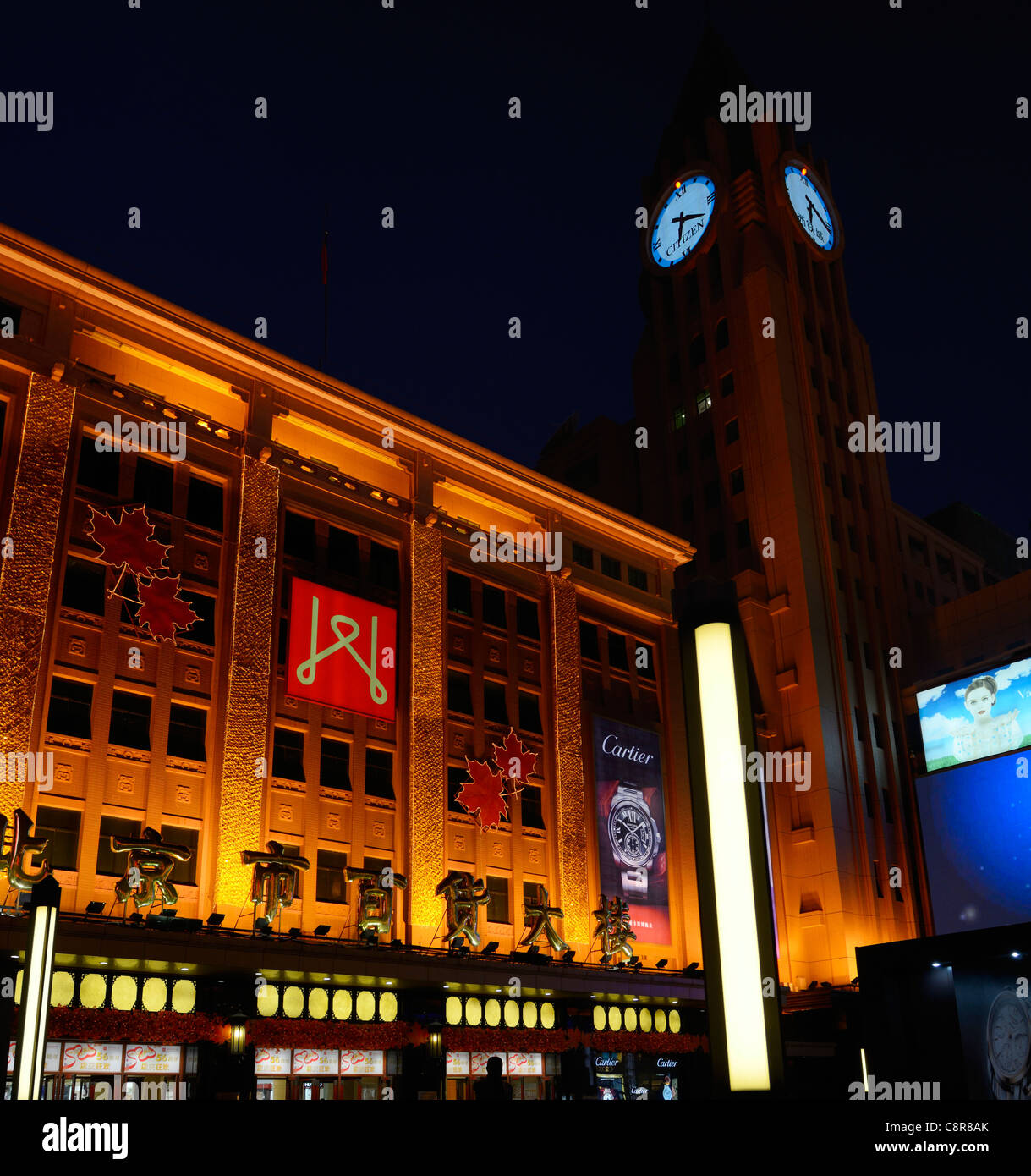La torre del reloj y el centro comercial de la calle Wangfujing Pekín por la noche, República Popular de China Foto de stock