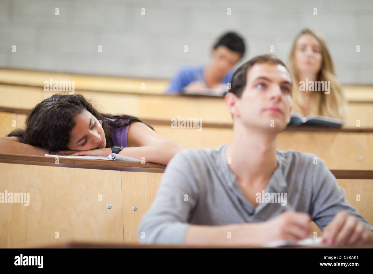 Estudiantes escuchando un profesor mientras su compañero está durmiendo Foto de stock