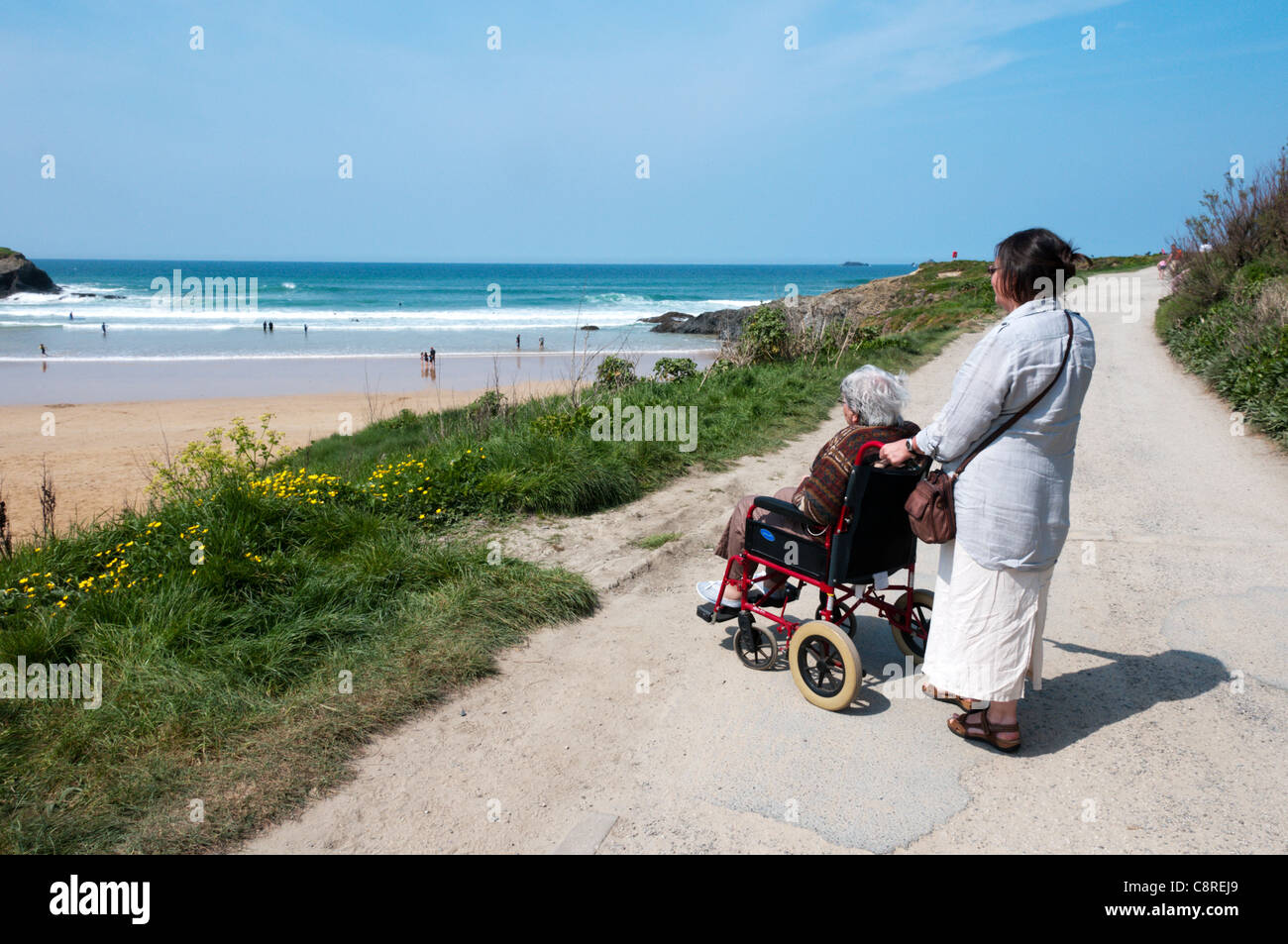Una mujer anciana con un cuidador o auxiliar en una ruta accesible para sillas de ruedas detrás de una playa de Cornualles. Modelo liberado. Foto de stock
