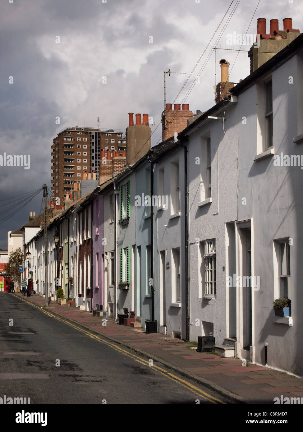 Una fila del lado iluminado casas adosadas y viviendas en una calle en Brighton, Inglaterra. Foto de stock