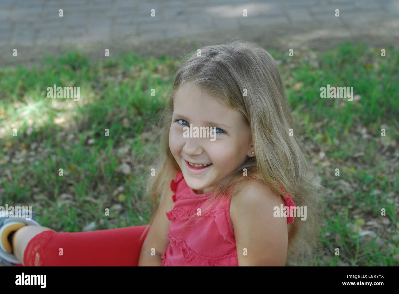 Retrato de risa chica en vestido rojo contra un fondo de hierba Foto de stock