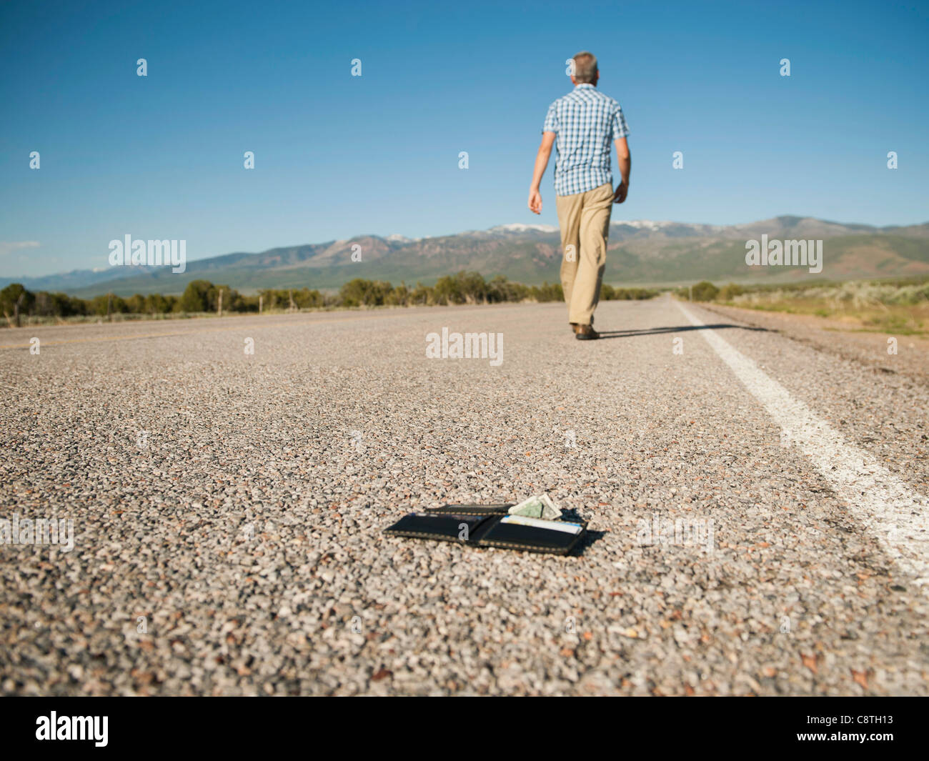 Estados Unidos, Utah, Kanosh, hombre caminando lejos dejando su billetera  detrás en carretera vacía Fotografía de stock - Alamy