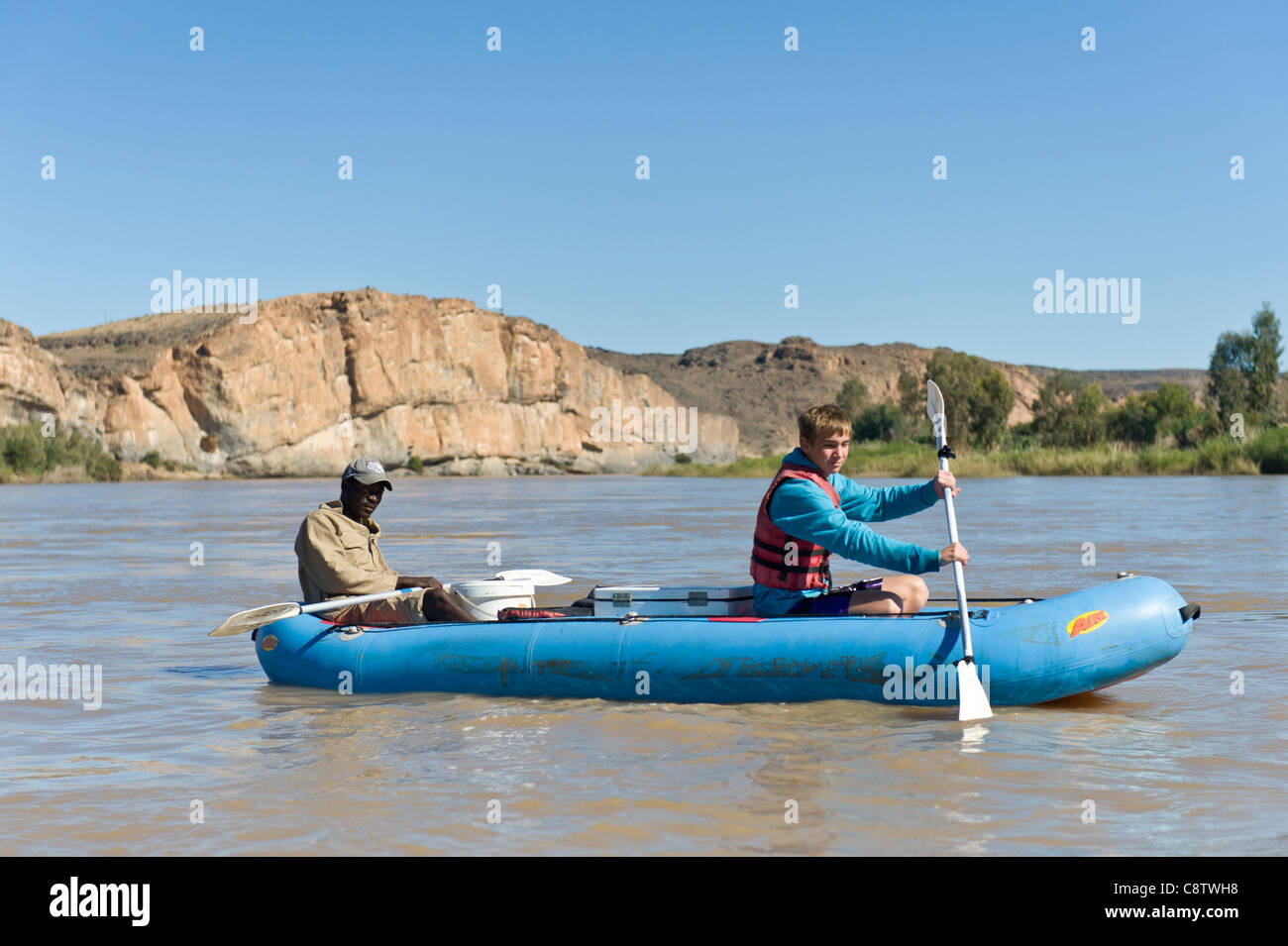 Tennager remando con una guía sobre el río Oranje, al oeste de Noordoewer Namibia Foto de stock