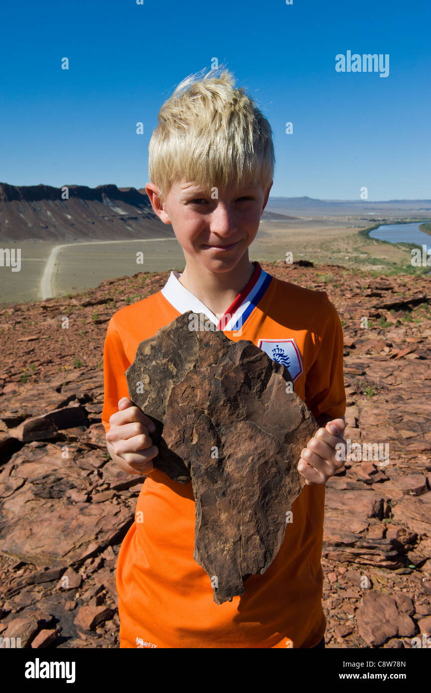 Niño sosteniendo una roca con forma del continente africano, Namibia Aussenkehr Foto de stock