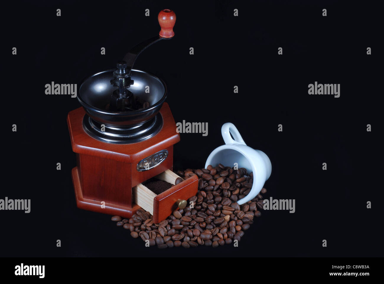 Molinillo de madera y granos de café y copa blanco Foto de stock