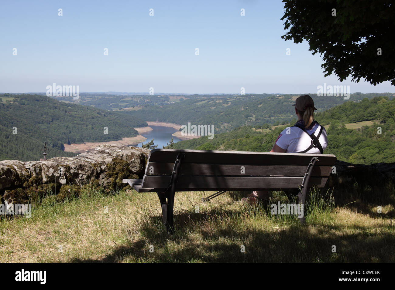 La mujer se sentó en un banco mirando por encima de un lago, vides, Francia, mayo de 2011 Foto de stock