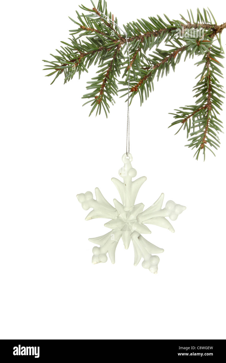Snowflake decoración colgando de la rama de un árbol de Navidad contra un blanco Foto de stock