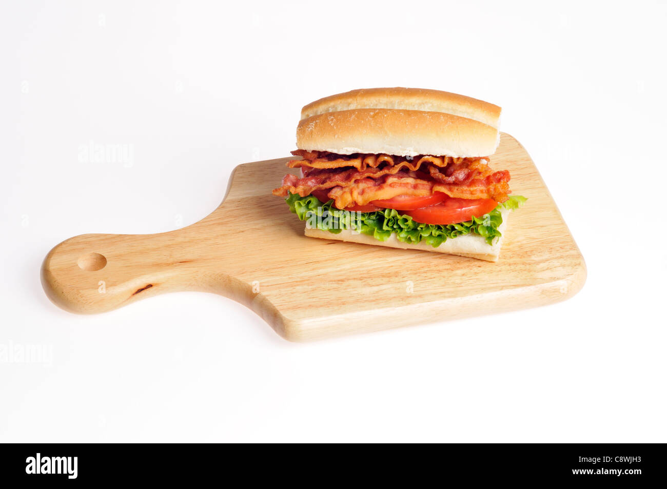 Bacon, lechuga y tomate BLT sándwich en un bollo de pan sobre una tabla de cortar de madera sobre un fondo blanco. Ee.Uu. Foto de stock