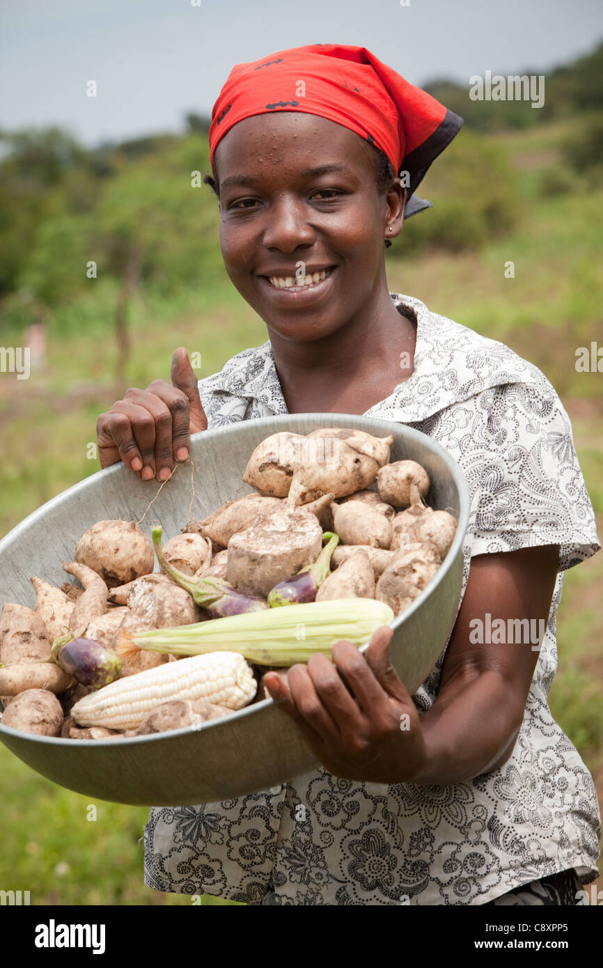 Una joven muestra una cosecha de batatas y verduras del jardín de la