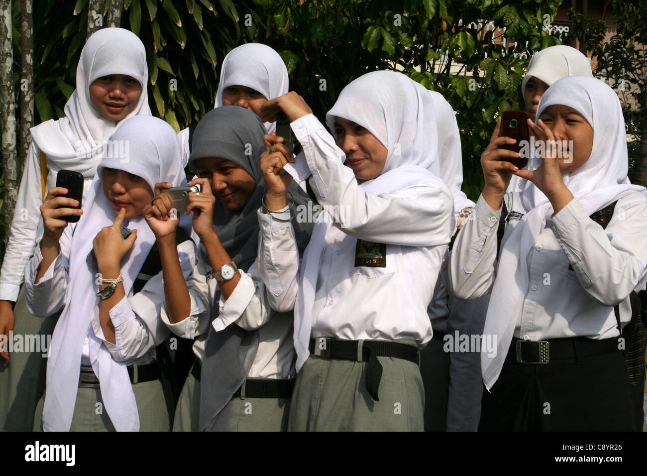 Alumnas musulmanas tomando fotos en sus teléfonos móviles Foto de stock