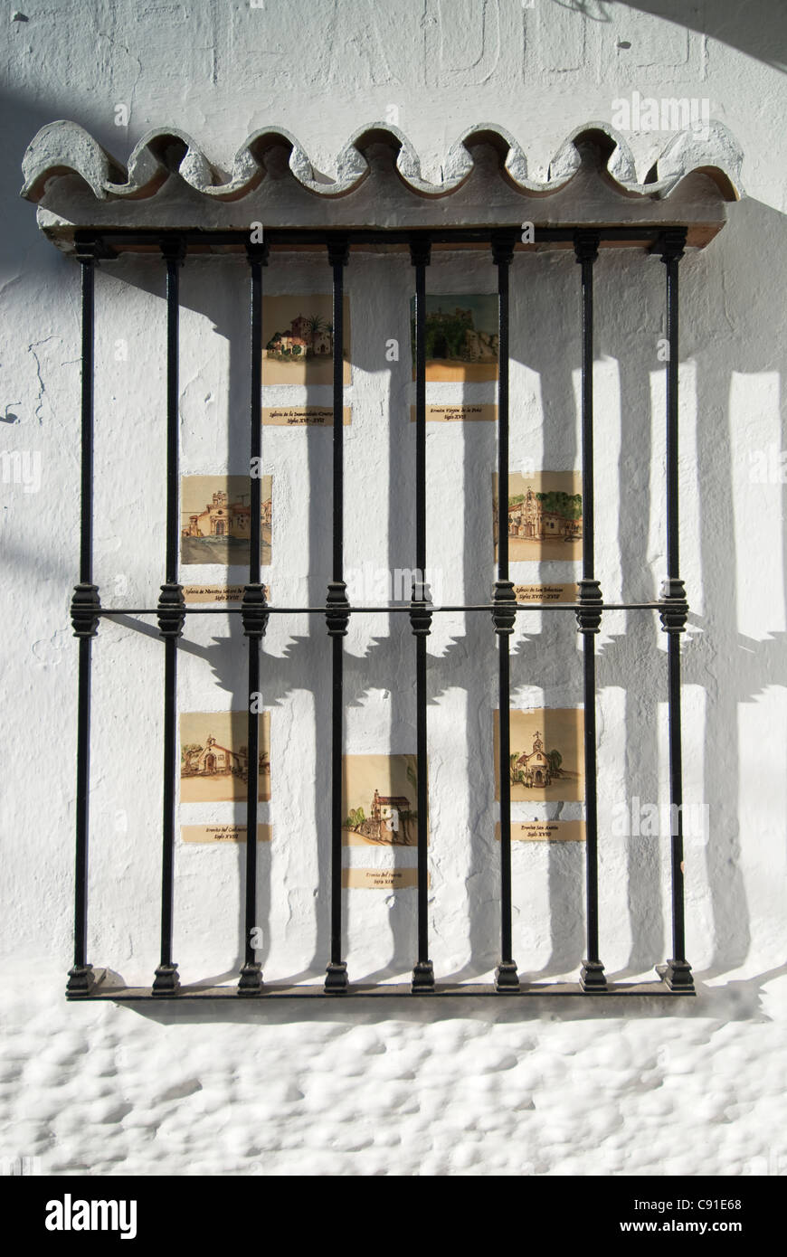 Azulejos con imágenes de iglesias locales decoran la pared de una calle de Mijas en colinas de la Sierra de Mijas. Foto de stock