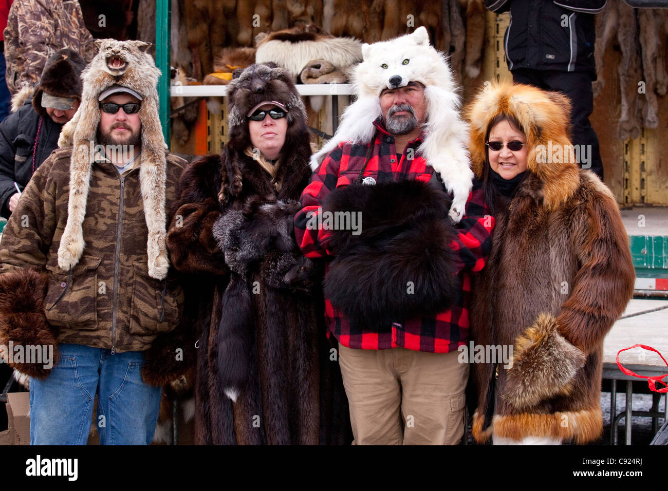 Cuatro espectadores vestidas con abrigos de piel y sombreros durante la subasta de pieles en Anchorage, 2011 Fur Rondy festival, Southcentral Alaska Foto de stock