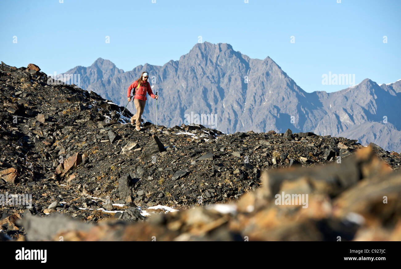 Mujer trekking sobre el sendero pasa el cuervo de la cresta rocosa, montañas Chugach, Alaska, Southcentral Otoño Foto de stock