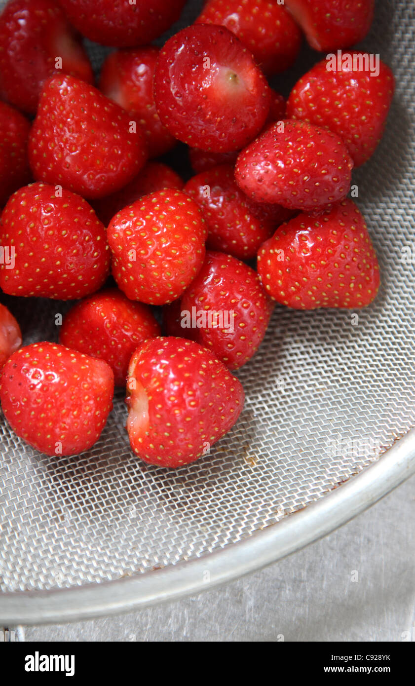 Las fresas maduras en un tamiz después del lavado Foto de stock