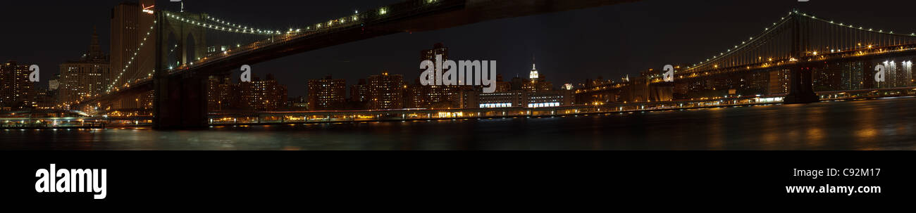 Vista desde Brooklyn Heights de Manhattan y Brooklyn Bridge de noche (pano) Foto de stock