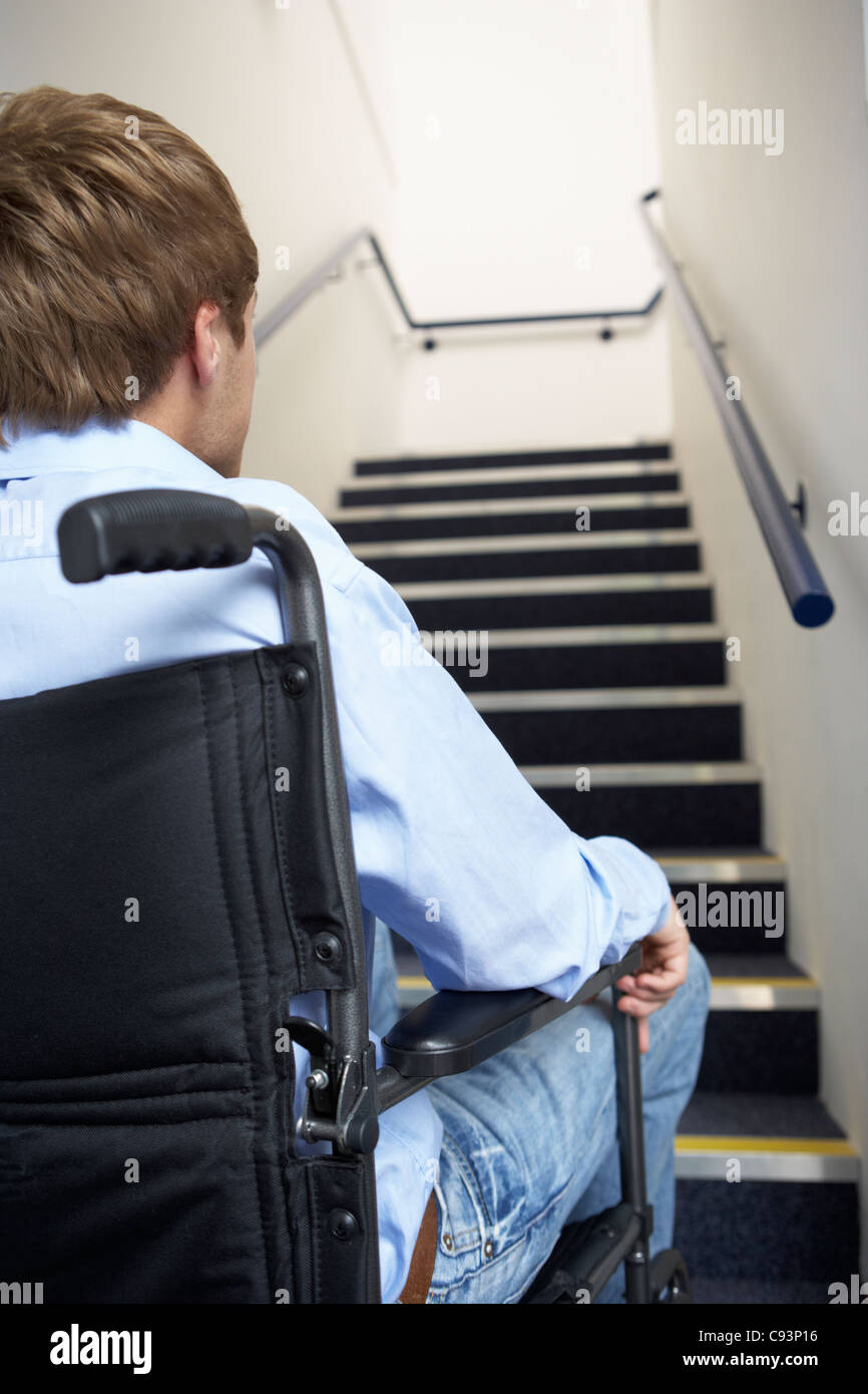 Hombre en silla de ruedas al pie de las escaleras Foto de stock