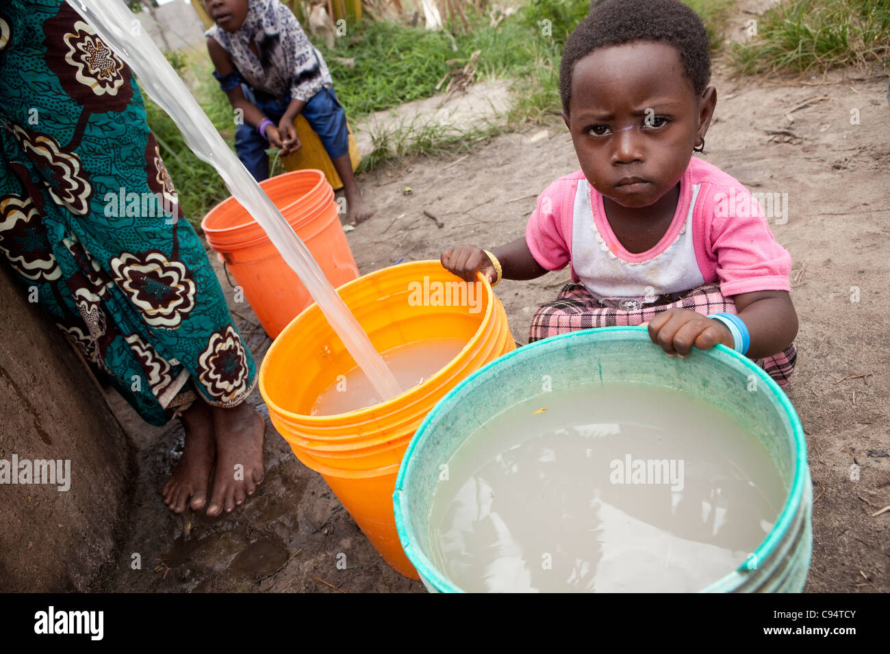 Un niño se sienta con agua sucia en un pozo fuera de Dar es Salaam, Tanzania, África Oriental. Foto de stock