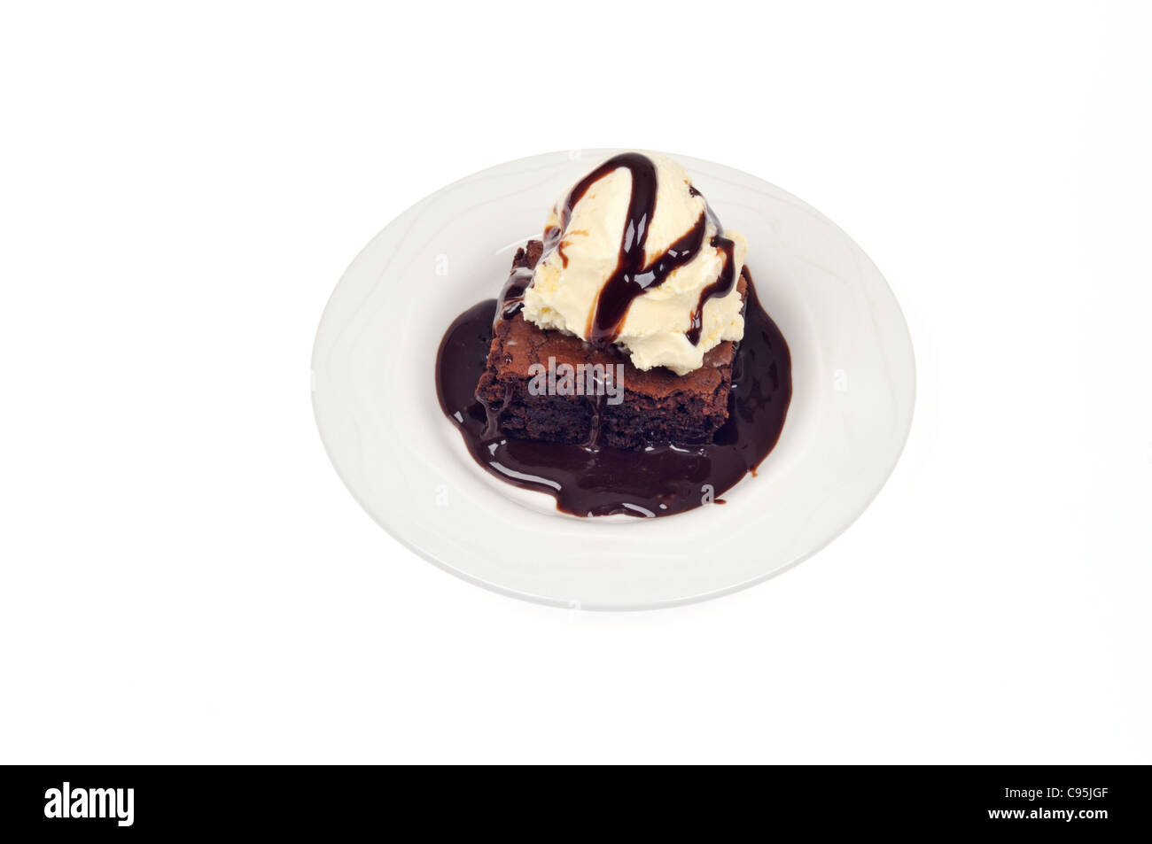 Fudge Brownie de chocolate y helado de vainilla con salsa de chocolate sobre la placa blanca sobre fondo blanco del recorte. Foto de stock