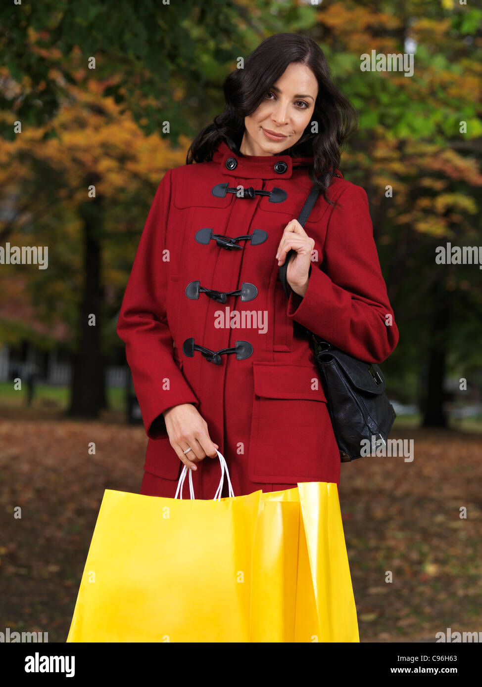 Hermosa joven mujer vistiendo una chaqueta roja y sosteniendo las bolsas de compras. Temporada de otoño de la moda. Foto de stock