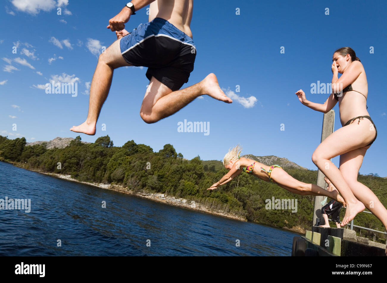 Un grupo saltando de un muelle en un lago. Lago Rosebery, Tullah, Tasmania, Australia Foto de stock