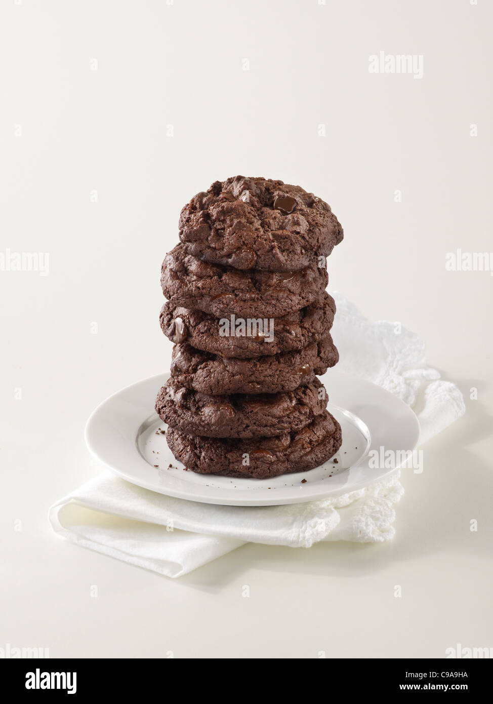 Una pila alta de triple gourmet chocolate chip cookies en una placa blanca. Foto de stock