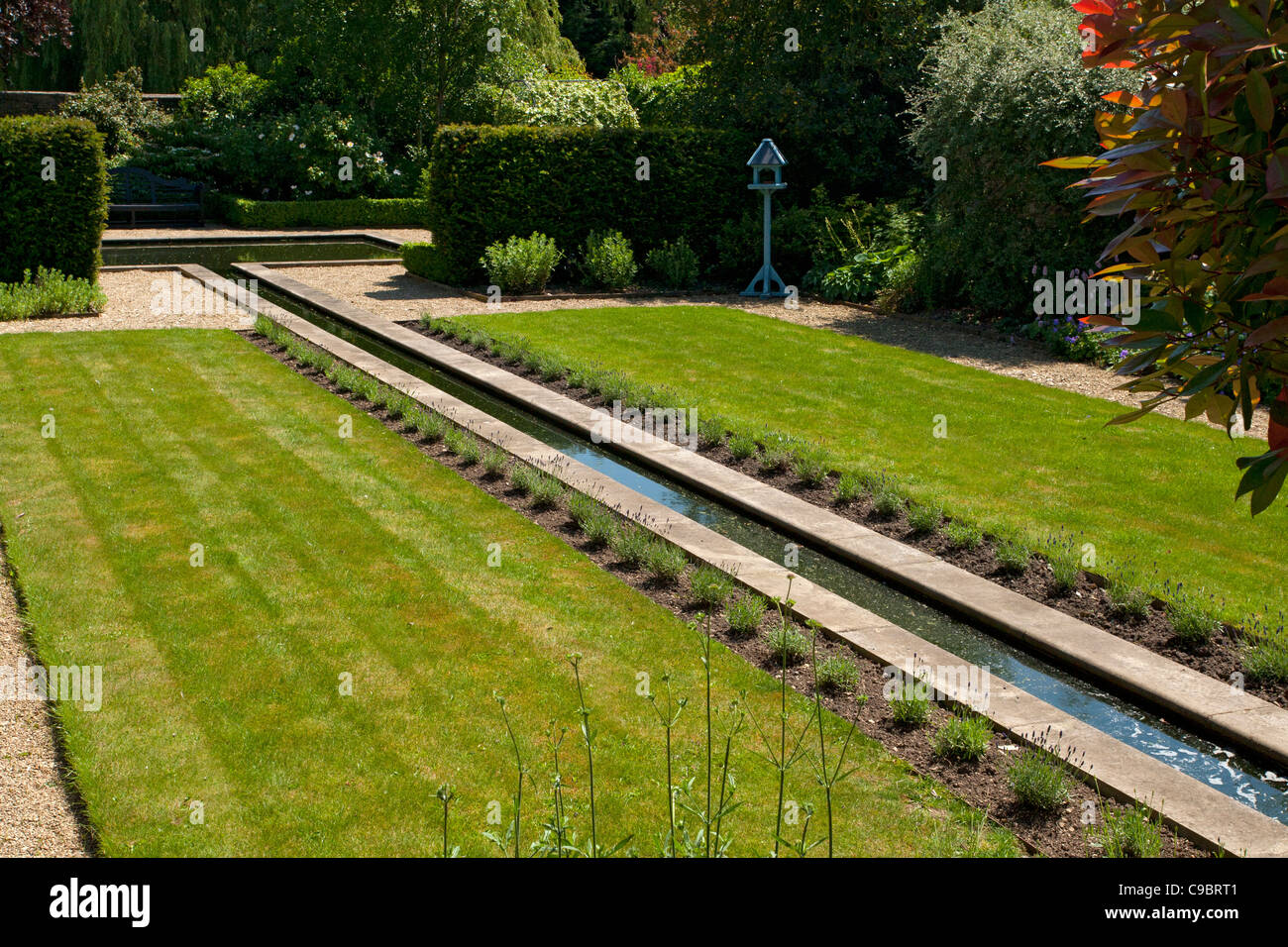 Rill característica del agua con bordes lavanda en jardín privado amurallado establecidos en un estilo formal con estanque como punto focal, Inglaterra. Foto de stock