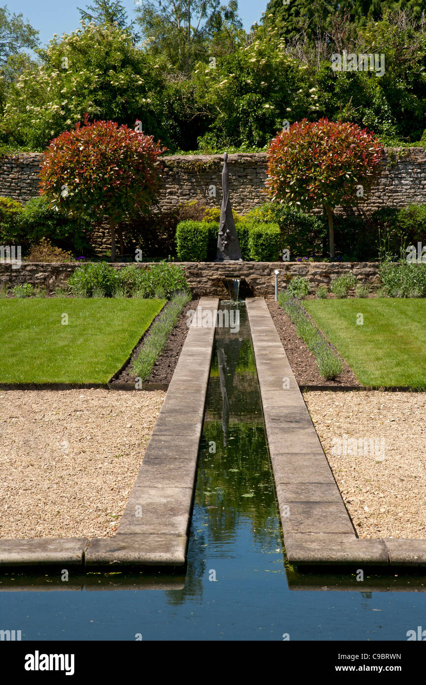 Rill característica del agua con bordes lavanda en jardín privado amurallado establecidos en un estilo formal con el obelisco como punto focal, Inglaterra. Foto de stock