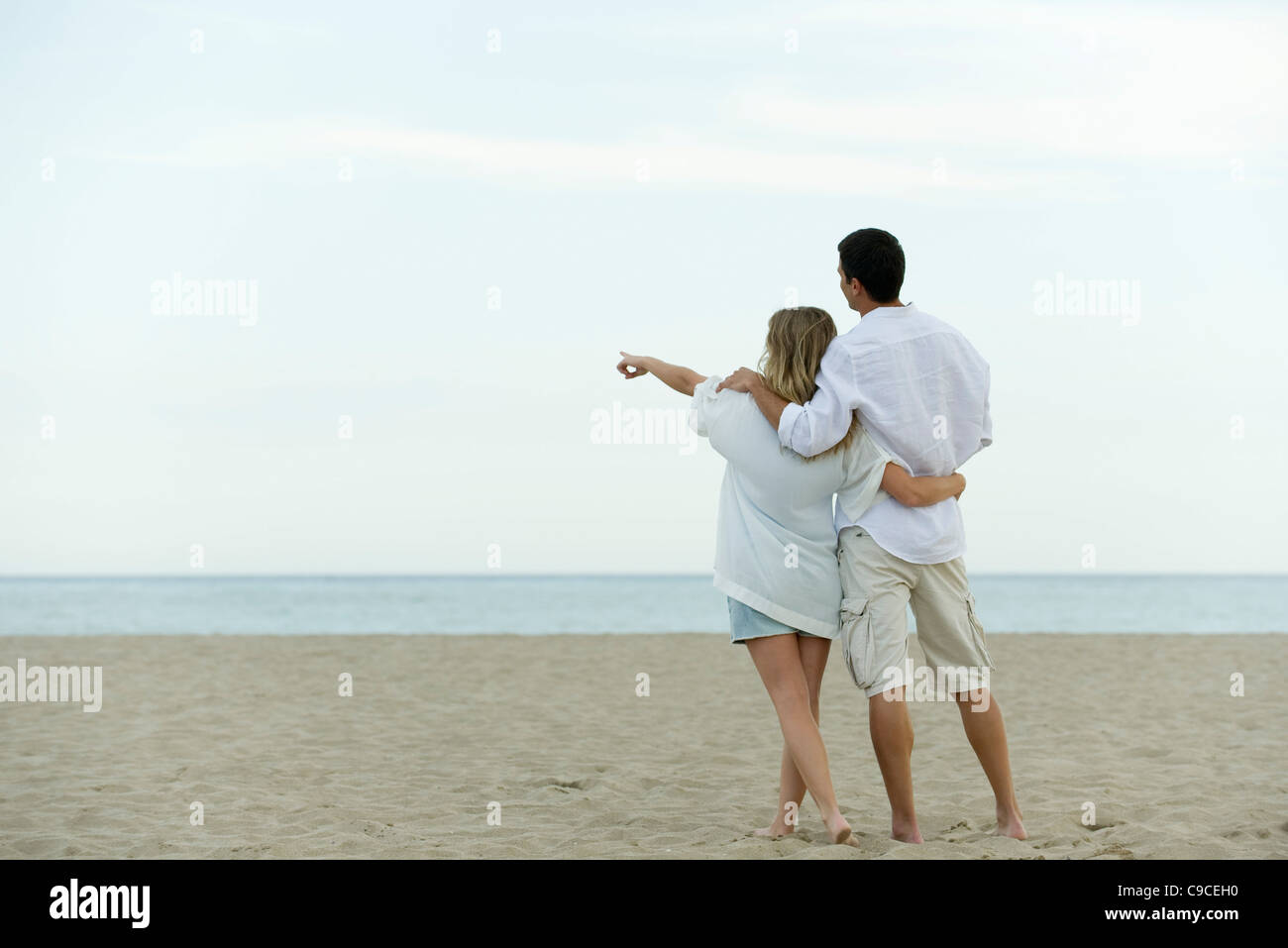 Pareja caminando juntos en la playa, mujer señalando en el mar Fotografía  de stock - Alamy