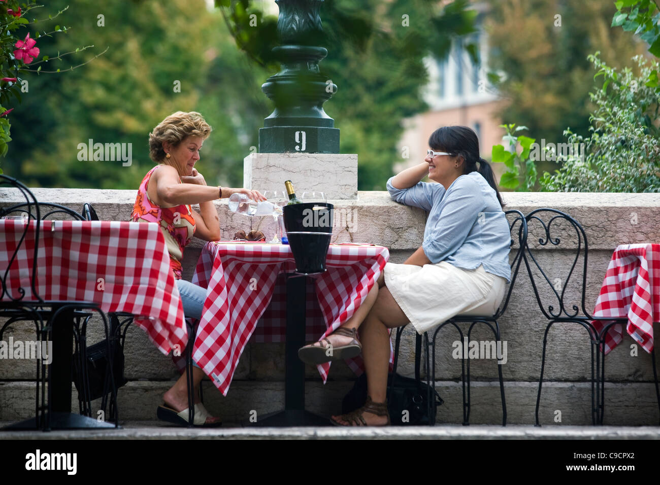 Dos mujeres sentadas en una mesa y hablar fuera de un restaurante en Verona, Italia Foto de stock